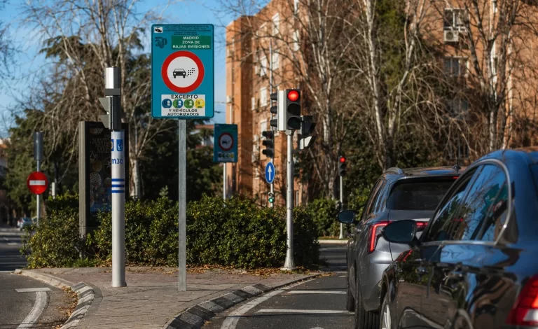 Señal de entrada a la Zona de Bajas Emisiones de Madrid junto a un semáforo en rojo y una cola de coches