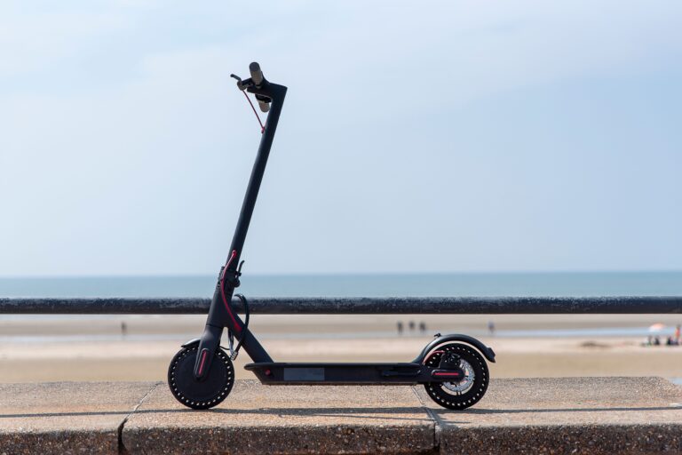 Patinete eléctrico negro estacionado junto a la barandilla de un paseo marítimo